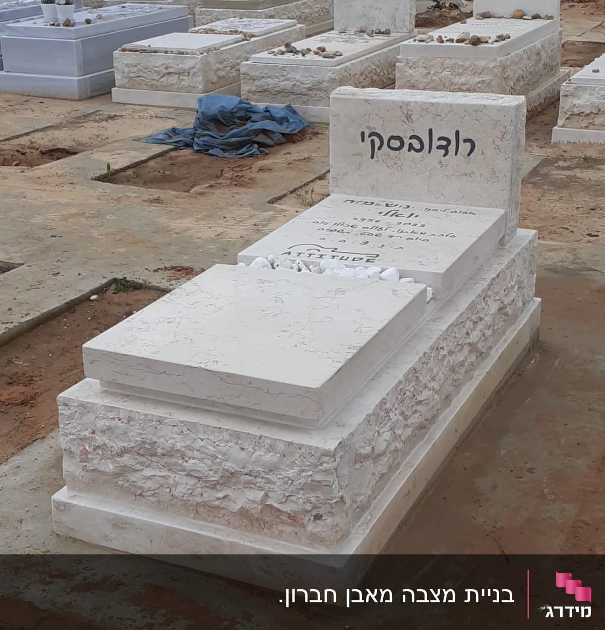 מצבות לבנות עם שמות ואבנים קטנות מונחות עליהן